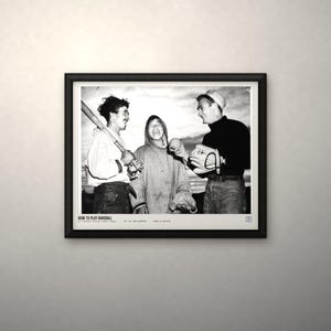 May include: A black and white framed photograph titled HOW TO PLAY BASEBALL featuring three individuals in casual clothing, one holding a baseball bat, another holding a baseball and glove, with text at the bottom including the National Archives logo.