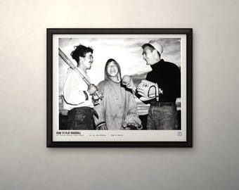 May include: A black and white framed photograph titled HOW TO PLAY BASEBALL featuring three individuals in casual clothing, one holding a baseball bat, another holding a baseball and glove, with text at the bottom including the National Archives logo.