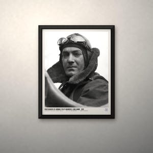 May include: A black and white framed photograph of airmail pilot Warren D. Williams from 1921. The pilot wears a leather aviator cap with goggles resting on the forehead. Text at the bottom reads: PHOTOGRAPH OF AIRMAIL PILOT WARREN D. WILLIAMS 1921.