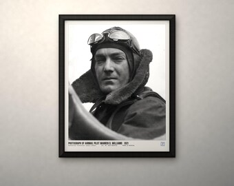 May include: A black and white framed photograph of airmail pilot Warren D. Williams from 1921. The pilot wears a leather aviator cap with goggles resting on the forehead. Text at the bottom reads: PHOTOGRAPH OF AIRMAIL PILOT WARREN D. WILLIAMS 1921.