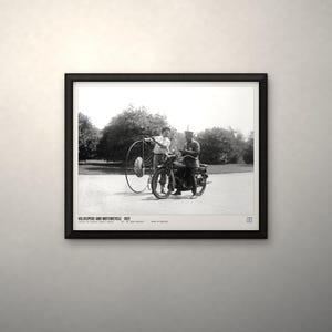 May include: A black and white framed print titled VELOCIPEDE AND MOTORCYCLE 1921. The image depicts a person standing next to a large-wheeled velocipede and another person seated on a motorcycle, with text at the bottom of the print.