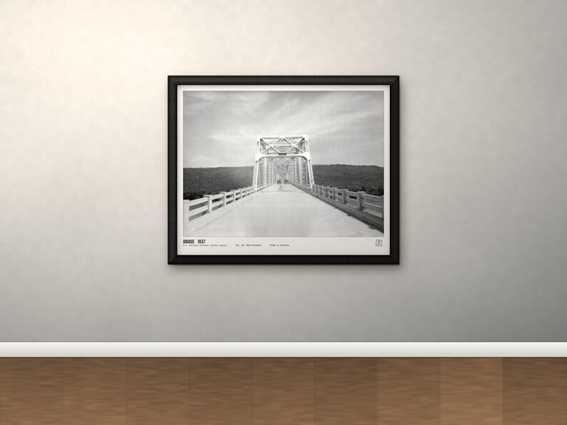 May include: A black and white framed wall art print featuring a perspective view of a truss bridge. The text at the bottom reads BRIDGE 1937, followed by smaller text including the location and date. The print is enclosed in a black frame.