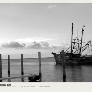 May include: A black and white photograph of a fishing boat moored near wooden pilings in calm water. The text WOE183 FISHING BOAT, U.S. National Archives (public domain), ACC. NO. 0024-66694268, FRAME 24 ARCHIVAL is printed at the bottom of the image.
