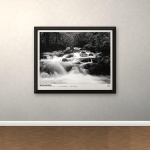 K&ouml;nnte beinhalten: Ein schwarz-wei&szlig; gerahmter Landschaftsdruck, der einen Wasserfall zeigt, der &uuml;ber dunkle Felsen flie&szlig;t. Der Druck enth&auml;lt einen wei&szlig;en Rand mit dem Text "MISTIGO WATERFALL" und weiteren kleinen gedruckten Details am unteren Bildrand.