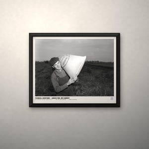 May include: A black and white framed photograph depicting a person in a cap and overalls carrying a large sack in a field. The text at the bottom reads: TECHNICAL ASSISTANCE - AGRICULTURE: RICE HARVEST. U.S. NATIONAL ARCHIVES (LOCAL ID: 306-PS-52-8574).