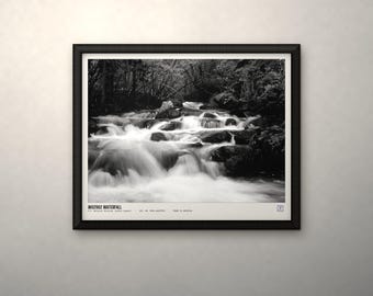 May include: A black and white framed photograph of a cascading waterfall flowing over dark rocks in a forest. The print features the text "WD2962 WATERFALL" in the bottom left corner, along with additional small printed details and a logo.