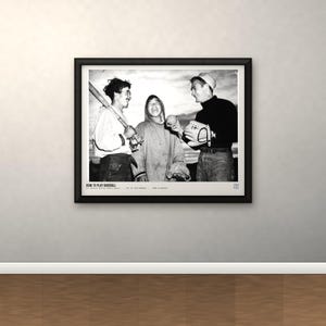 May include: A black and white framed photograph depicting three individuals engaged in baseball activities. The left figure holds a bat, the center figure laughs, and the right figure holds a ball and glove. Text at the bottom reads HOW TO PLAY BASEBALL.