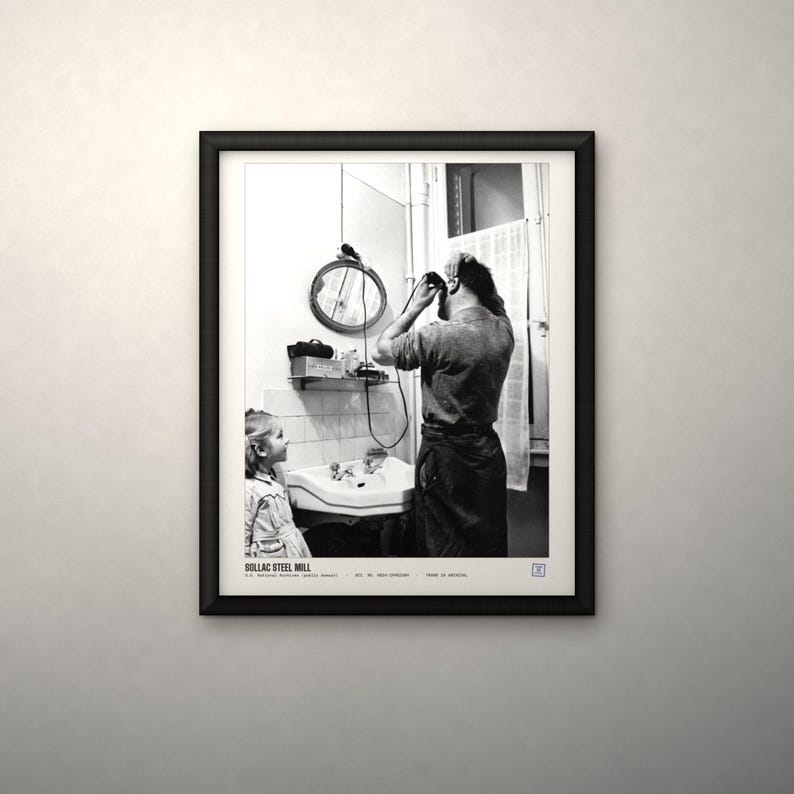 May include: A black and white framed photograph titled SOLLAC STEEL MILL. The image depicts a person using an electric shaver in a bathroom while a child watches. A round mirror, a sink, and a window with a curtain are visible in the background.