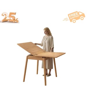 May include: A light-colored wooden dining table with a rectangular top that features a hinged leaf mechanism, allowing the surface to fold open. The table is supported by four straight, tapered legs and displays a natural wood grain finish throughout.