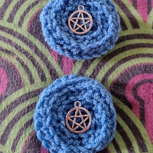 May include: Two blue crocheted circles with a silver pentagram charm in the center of each.