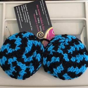 Może przedstawiać: Dwa ciepłe nauszniki wykonane na szydełku w czarno-niebieskim wzorze geometrycznym. Nauszniki są ręcznie robione w Szkocji.