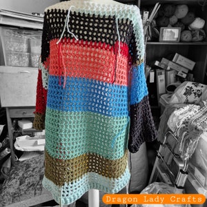 May include: A multi-colored crochet top with a striped pattern in black, red, blue, green, and brown. The top is made with a loose, open stitch and has a wide, flowing neckline.