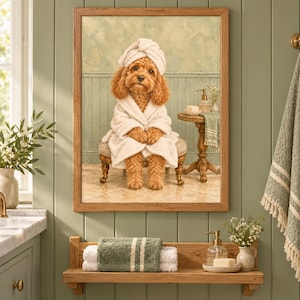 Puede incluir: Una impresión artística enmarcada que muestra a un perro de color marrón dorado con una bata de baño blanca de felpa y una toalla a juego en la cabeza, sentado en un taburete pequeño en un baño con una mesa auxiliar.