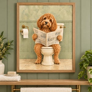 Puede incluir: Una impresión artística enmarcada que muestra a un perro de pelaje rizado color marrón dorado sentado en un inodoro blanco mientras lee un periódico. La escena se sitúa frente a una pared de paneles verde claro con un portarrollos.