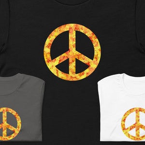 Puede incluir: Tres camisetas con un diseño de signo de paz. El signo de paz es amarillo y naranja con un efecto acuarela. Las camisetas son negra, gris y blanca.