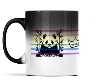 May include: A ceramic mug with a black handle and a gradient finish that transitions from black at the top to white at the bottom. The center features a black graphic of a panda sitting among bamboo stalks, overlaid with horizontal rainbow stripes and a crown.