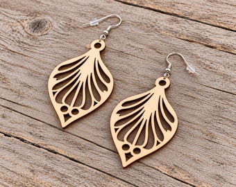 May include: A pair of light brown wooden drop earrings featuring a laser-cut teardrop shape with an intricate fan-like pattern and three small circular cutouts at the bottom. The earrings are attached to silver-toned metal fishhook ear wires.