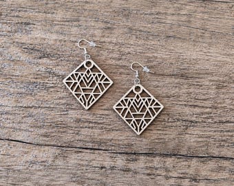 May include: A pair of light-colored wooden earrings featuring a diamond-shaped cutout design with intricate geometric lines. Each earring is suspended from a silver-toned metal hook with a small clear plastic backing for secure placement.