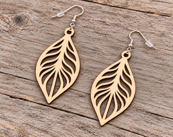 May include: A pair of light brown wooden earrings shaped like leaves with intricate cut-out vein patterns. Each earring features a silver-toned metal fishhook wire with a small clear plastic backing for secure placement on the earlobe.