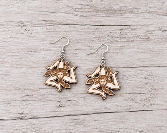 May include: A pair of dangle earrings featuring a light-colored wood cutout of the Triskelion symbol, which depicts three bent legs radiating from a central head with wheat stalks, attached to silver-toned metal earring hooks for pierced ears.