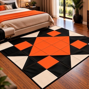 Puede incluir: Una alfombra rectangular con un patrón geométrico de triángulos y cuadrados en negro, naranja brillante y blanco roto. El diseño consiste en una gran forma de estrella naranja central rodeada por bloques geométricos negros y blancos alternos.