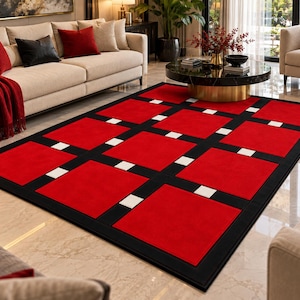 May include: A rectangular area rug featuring a grid pattern of large red squares separated by thick black bands and small white square accents at the intersections. The rug has a solid black border framing the entire geometric design.