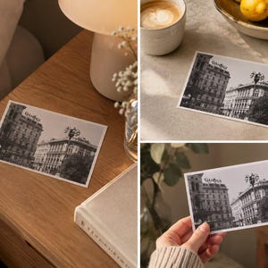 Puede incluir: Una postal rectangular que presenta una fotografía en blanco y negro de una escena de calle urbana con edificios históricos y una farola. La palabra GUCCI está impresa en una fuente estilizada en la parte superior central de la imagen.