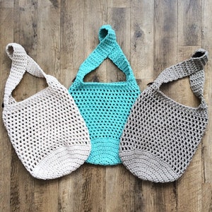 K&ouml;nnte beinhalten: Drei geh&auml;kelte Einkaufstaschen in verschiedenen Farben: beige, t&uuml;rkis und grau. Die Taschen sind mit einem einfachen Netz-Muster gearbeitet und haben einen einzigen Trageriemen.