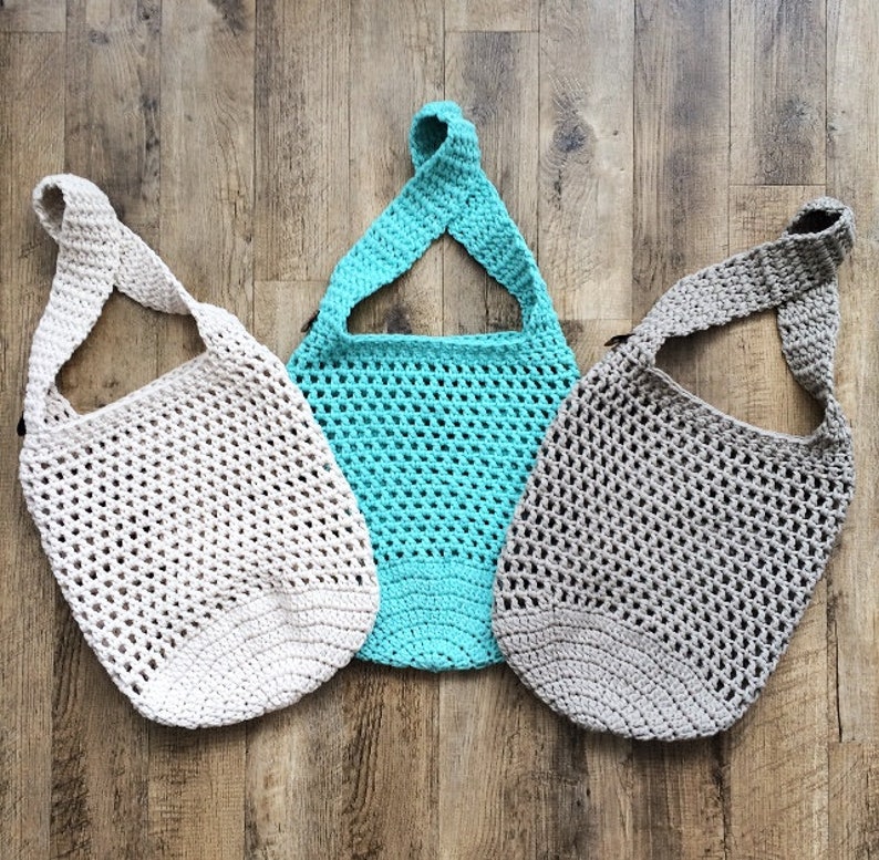 K&ouml;nnte beinhalten: Drei geh&auml;kelte Einkaufstaschen in verschiedenen Farben: beige, t&uuml;rkis und grau. Die Taschen sind mit einem einfachen Netz-Muster gearbeitet und haben einen einzigen Trageriemen.