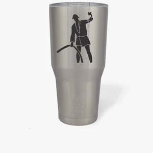 May include: A stainless steel tumbler with a black silhouette of a person in a robe holding a cup and a hose. The tumbler has a black inscription that reads "The 90's"