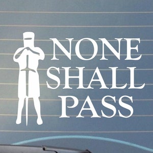 May include: White vinyl decal featuring a medieval knight holding a sword, with the words "NONE SHALL PASS" in bold, uppercase letters. The decal is designed for application on a car window or similar surface.