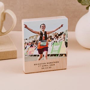 May include: A wooden photo block with a picture of a woman running a marathon. The block has the text "Brighton Marathon 7th April 2024 04:12:32" printed on the bottom.