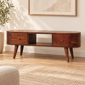 May include: A dark brown wooden media console with rounded edges, featuring two drawers with small round metal knobs and a central open storage shelf. The unit is supported by four tapered wooden legs that angle outward from the base.