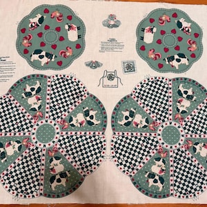 May include: A printed fabric panel featuring cow motifs, red hearts, and green checkered patterns. The design includes circular and fan-shaped segments with instructional text for sewing projects, including text labeled Creative Suggestions.