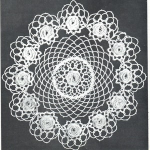 May include: White crocheted doily with a circular design and a central flower motif. The doily has a scalloped edge and is surrounded by a ring of smaller flowers.