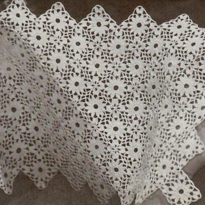 Puede incluir: Doily de ganchillo blanco con borde festoneado y un patrón de flores repetido.