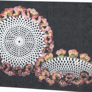 Könnte beinhalten: Zwei weiße Häkeldeckchen mit einem floralen Design in Rosa-, Gelb- und Orangetönen.