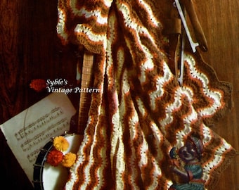 May include: A crocheted blanket with brown, white, and orange stripes. The blanket is draped over a banjo and a pair of ice skates. The text "Syble's Vintage Patterns" is visible in the image.