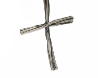 May include: A silver cross made of twisted wire.