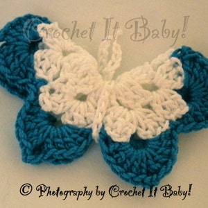 May include: A crocheted butterfly with white and teal blue wings. The butterfly is made with a delicate, lacy stitch.