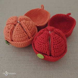 May include: Four crocheted pumpkin-shaped baskets, two orange and two red, with green buttons. The baskets are open and show the crocheted interior.