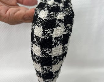 May include: Black and white checkered headband. The headband is made of a soft, woven fabric.
