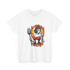 May include: A white short-sleeve t-shirt featuring a graphic print of a character with dark hair, red horns, and a red top, holding a large black pitchfork. The character is surrounded by orange and yellow flames in a circular design.