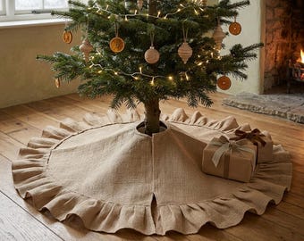 Può includere: Una gonna per albero di Natale circolare in iuta color marrone chiaro con un ampio bordo arricciato. La gonna è posizionata alla base di un albero di Natale verde decorato con luci bianche calde, ornamenti in legno e fette d'arancia.