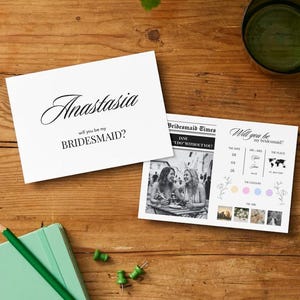 Può includere: Un biglietto pieghevole bianco con il testo Anastasia will you be my BRIDESMAID? e un biglietto rettangolare abbinato con una foto in bianco e nero, il testo Bridesmaid Times e sezioni per data, ora, luogo e campioni di colore.