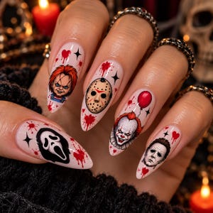Op de afbeelding: Amandelvormige press-on nagels met illustraties van horrorfilmfiguren zoals Chucky, een ijshockeymasker, Pennywise met een rode ballon, Michael Myers en het Ghostface-masker, geaccentueerd met rode bloedspatten en zwarte stermotieven.