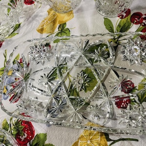 May include: A rectangular clear glass serving tray featuring a pressed starburst pattern with multiple faceted points. The tray has a scalloped edge and a geometric design of intersecting lines and star motifs across the entire surface.