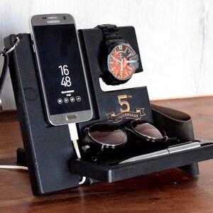 Puede incluir: Organizador de madera negro con ranuras para un tel&eacute;fono, un reloj, gafas de sol y un bol&iacute;grafo. El organizador tiene una inscripci&oacute;n de 5&ordm; aniversario y un gancho para llaves.