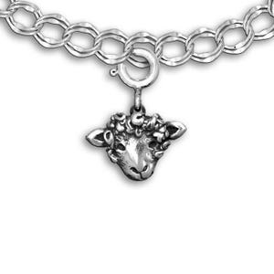 Könnte beinhalten: Ein silbernes Charm-Armband mit einem Schafskopf-Anhänger. Der Charm zeigt einen Schafskopf mit lockigem Fell. Das Armband hat eine Doppelglieder-Kette und einen sicheren Verschluss.
