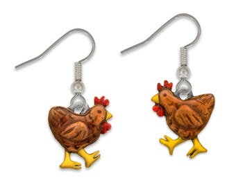 May include: A pair of silver dangle earrings featuring a brown chicken with red and yellow accents. The chicken is depicted walking with its head turned to the side.